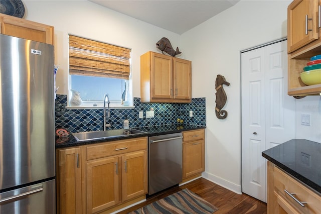 kitchen with appliances with stainless steel finishes, sink, tasteful backsplash, dark stone counters, and dark hardwood / wood-style floors