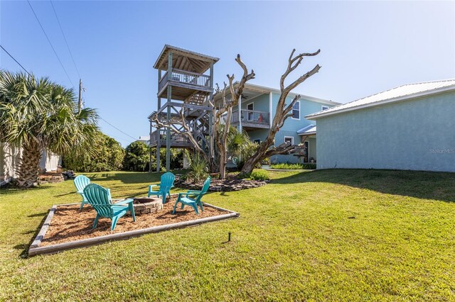 view of yard featuring a balcony and an outdoor fire pit