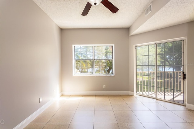 unfurnished room featuring ceiling fan, light tile patterned floors, and a textured ceiling