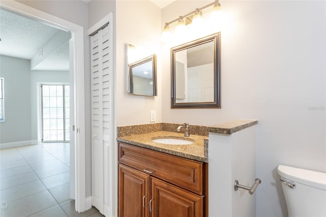 bathroom with tile patterned flooring, vanity, a textured ceiling, and toilet