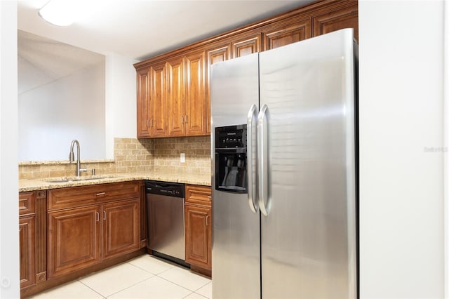 kitchen with appliances with stainless steel finishes, light stone countertops, sink, and light tile patterned floors