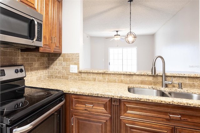 kitchen featuring sink, decorative light fixtures, a textured ceiling, stainless steel appliances, and decorative backsplash