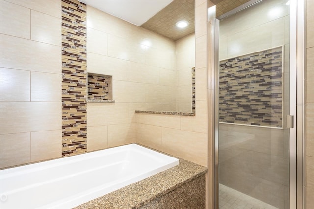 bathroom with tile walls and plus walk in shower