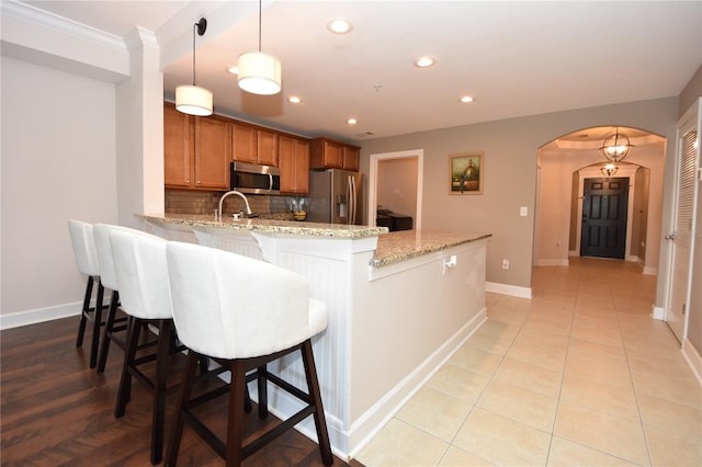 kitchen with backsplash, stainless steel appliances, a breakfast bar, and light stone countertops