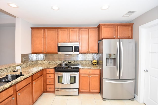 kitchen featuring light stone countertops, appliances with stainless steel finishes, sink, light tile floors, and tasteful backsplash