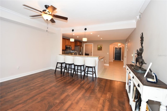 kitchen with hanging light fixtures, appliances with stainless steel finishes, hardwood / wood-style flooring, and kitchen peninsula