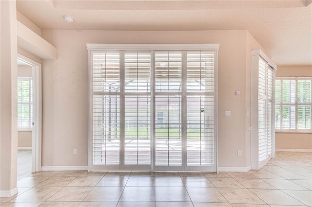 entryway with plenty of natural light, light tile patterned floors, and a textured ceiling