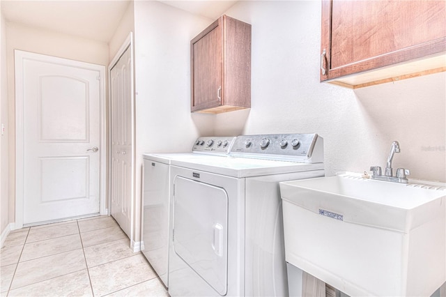 washroom with cabinets, sink, light tile patterned flooring, and washing machine and clothes dryer