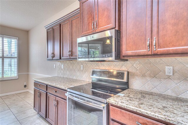 kitchen featuring backsplash, light stone countertops, light tile patterned floors, and appliances with stainless steel finishes