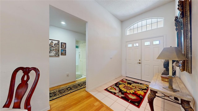 foyer with a textured ceiling, lofted ceiling, and hardwood / wood-style floors