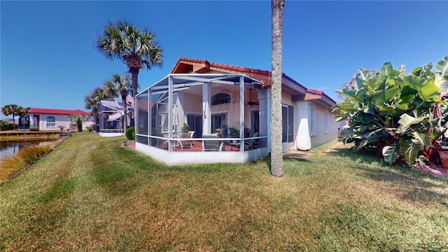 rear view of house with a yard and a lanai