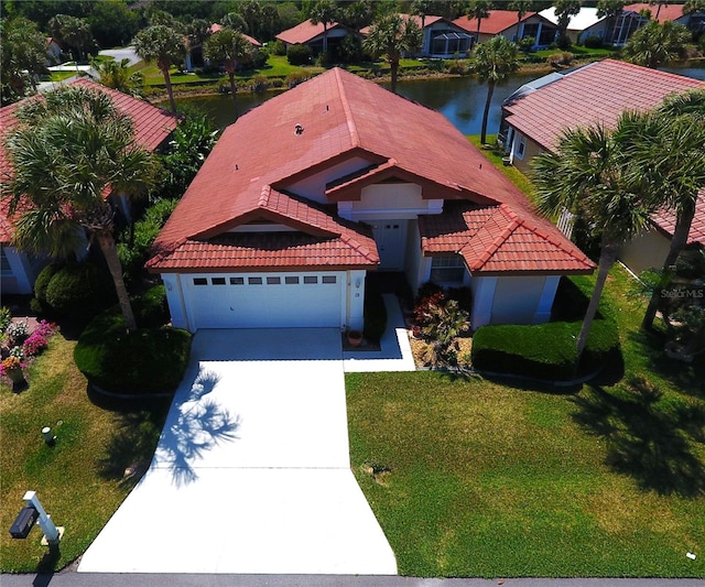 view of front of home with a front yard, a garage, and a water view