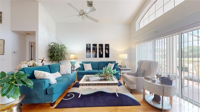 living room with a towering ceiling, ceiling fan, and light hardwood / wood-style floors