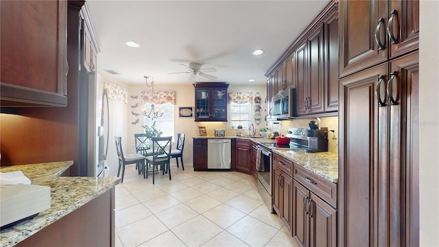 kitchen featuring hanging light fixtures, light stone countertops, stainless steel appliances, ceiling fan, and light tile floors