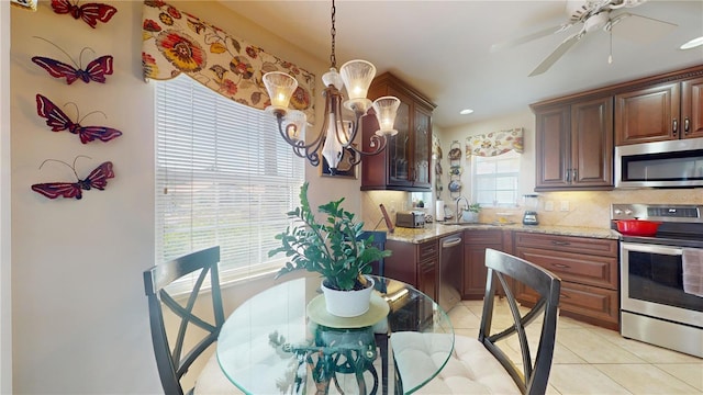 kitchen featuring light stone countertops, appliances with stainless steel finishes, sink, tasteful backsplash, and light tile flooring