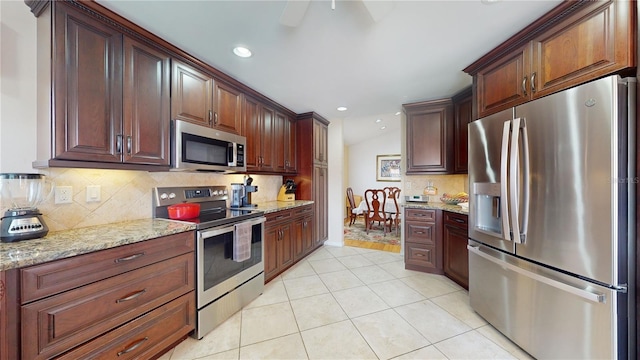 kitchen featuring appliances with stainless steel finishes, light stone counters, backsplash, ceiling fan, and light tile floors