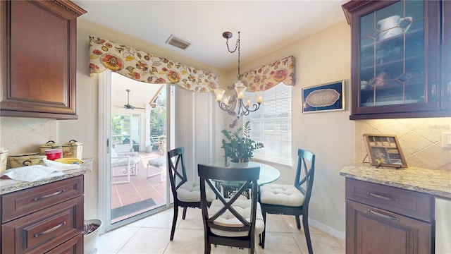 tiled dining space with ceiling fan with notable chandelier