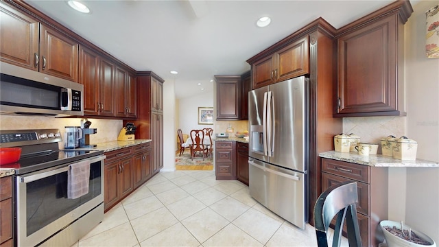 kitchen with light tile floors, tasteful backsplash, light stone counters, and stainless steel appliances