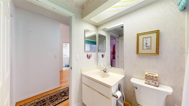 bathroom with large vanity, toilet, and hardwood / wood-style floors