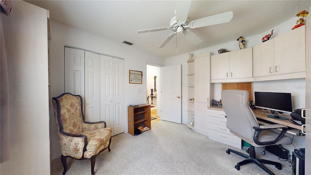 carpeted office space featuring ceiling fan and a textured ceiling