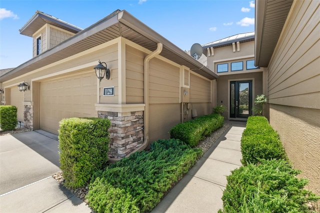 doorway to property with concrete driveway, a garage, and stone siding