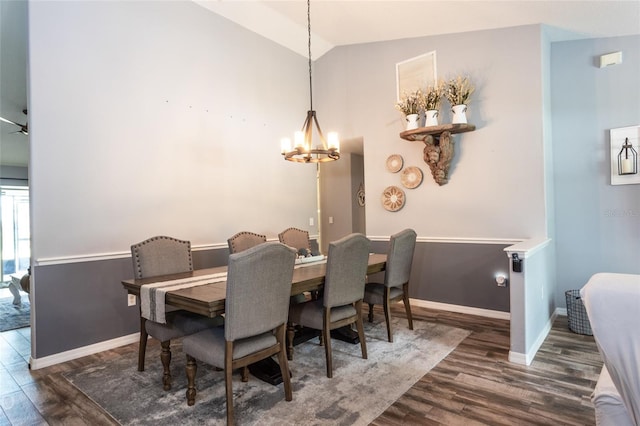 dining space featuring dark hardwood / wood-style flooring, vaulted ceiling, and a notable chandelier