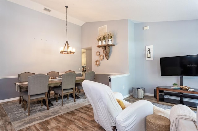 living room featuring dark hardwood / wood-style floors, vaulted ceiling, and a notable chandelier