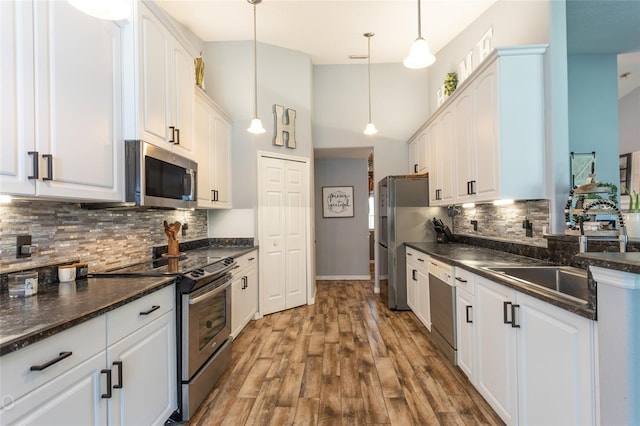 kitchen with appliances with stainless steel finishes, decorative light fixtures, and white cabinets