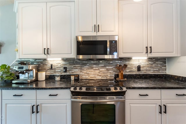 kitchen with white cabinetry, appliances with stainless steel finishes, backsplash, and dark stone counters