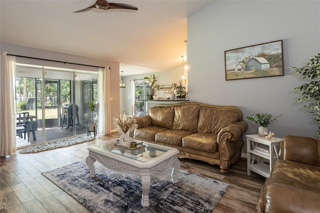 living room with ceiling fan, vaulted ceiling, and light hardwood / wood-style flooring