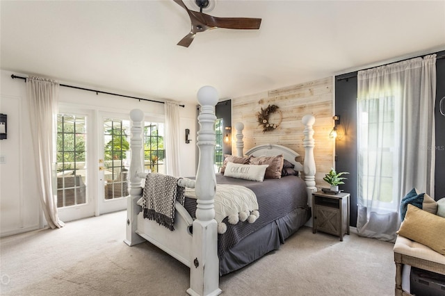 bedroom with light carpet, access to exterior, ceiling fan, and wood walls