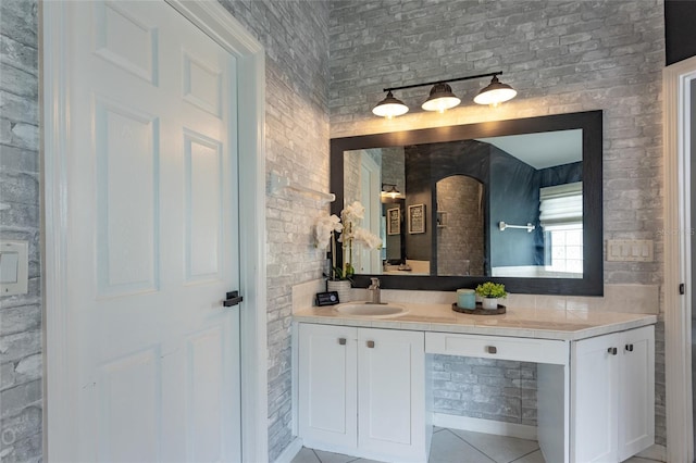 bathroom with vanity, tile patterned flooring, and brick wall