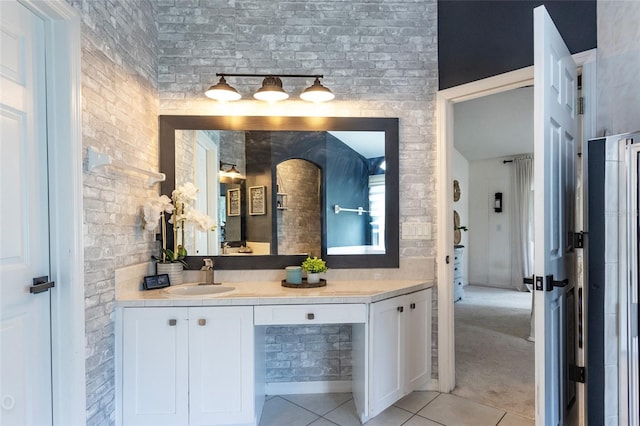 bathroom with tile patterned flooring, vanity, and brick wall