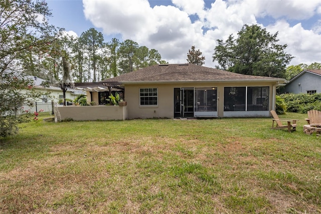 back of house with a fire pit, a sunroom, and a lawn