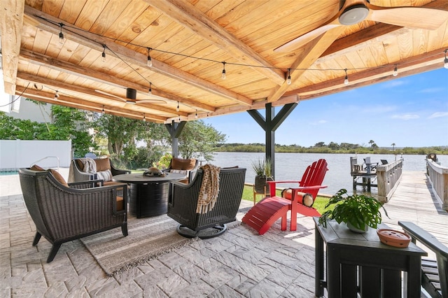 view of terrace featuring a water view, ceiling fan, and an outdoor fire pit