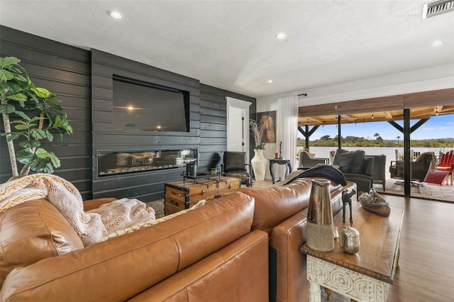 living room with hardwood / wood-style flooring, wooden walls, and a textured ceiling