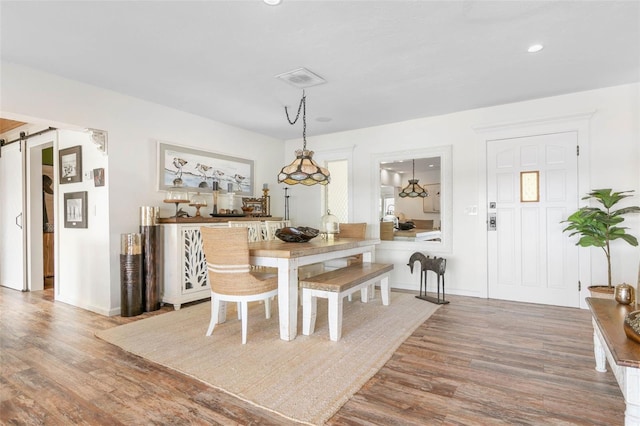 dining space with a barn door and hardwood / wood-style floors