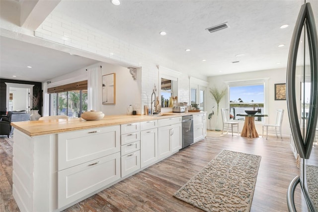 kitchen with butcher block countertops, white cabinets, dishwasher, sink, and wood-type flooring