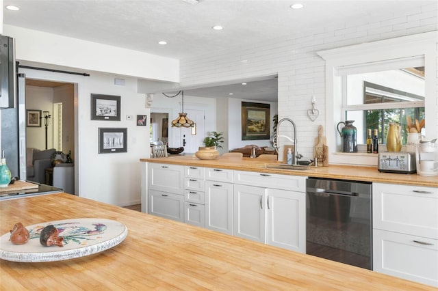 kitchen with a barn door, black dishwasher, white cabinetry, sink, and pendant lighting