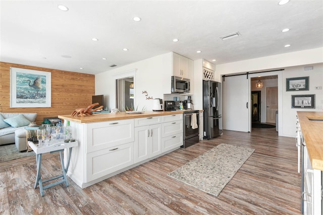 kitchen with wooden counters, light hardwood / wood-style flooring, white cabinets, and stainless steel appliances