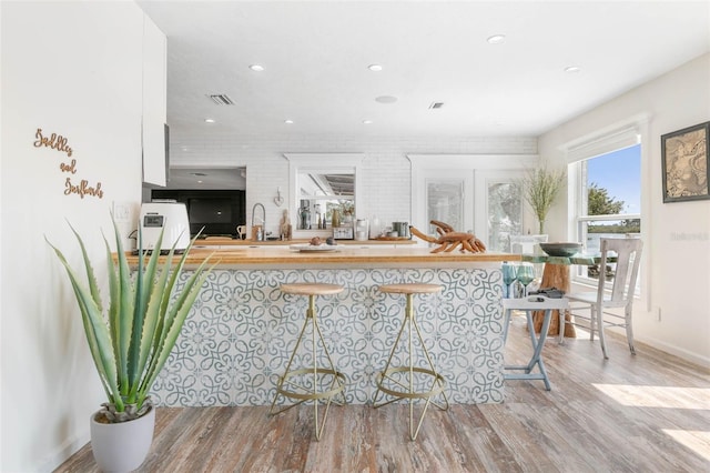 interior space featuring light hardwood / wood-style flooring, sink, and brick wall