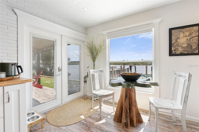 sitting room featuring french doors, brick wall, a water view, and hardwood / wood-style flooring