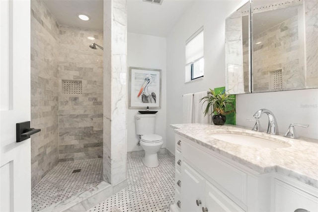 bathroom featuring tiled shower, toilet, tile floors, and large vanity