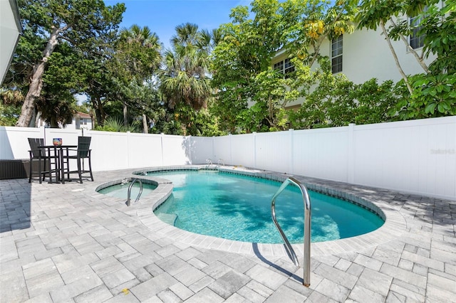 view of swimming pool featuring a patio and an in ground hot tub