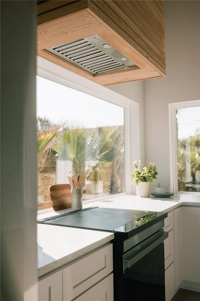 kitchen with a wealth of natural light, white cabinetry, and electric range