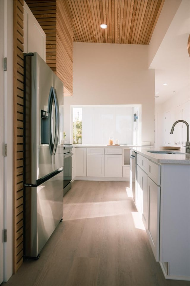 kitchen featuring light wood-type flooring, stainless steel appliances, sink, wooden ceiling, and white cabinets