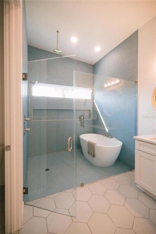 bathroom featuring tile patterned flooring, vanity, tile walls, and plus walk in shower