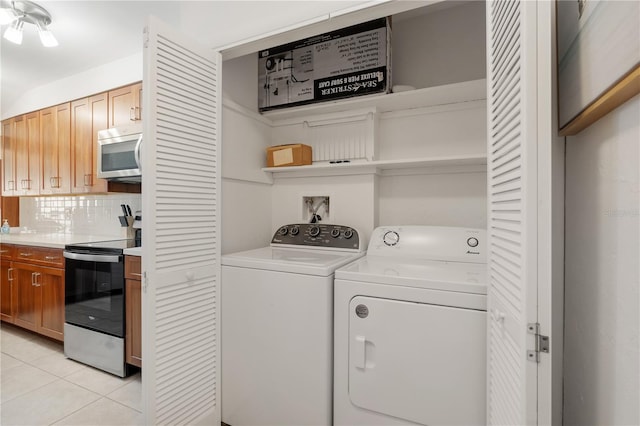 clothes washing area with washing machine and dryer and light tile patterned floors