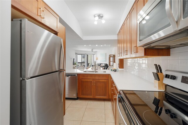 kitchen with sink, tasteful backsplash, vaulted ceiling, light tile patterned flooring, and appliances with stainless steel finishes