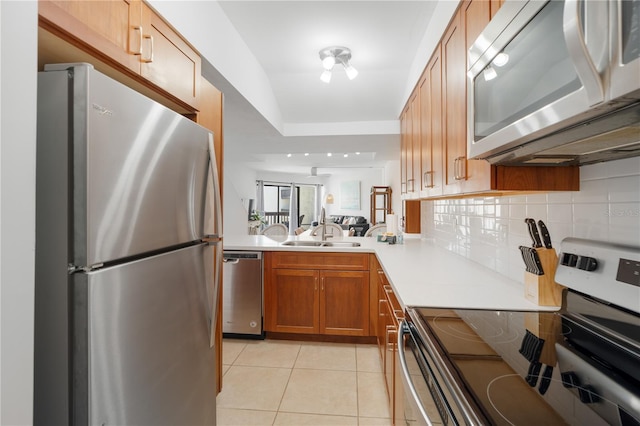 kitchen featuring appliances with stainless steel finishes, sink, light tile patterned floors, and decorative backsplash